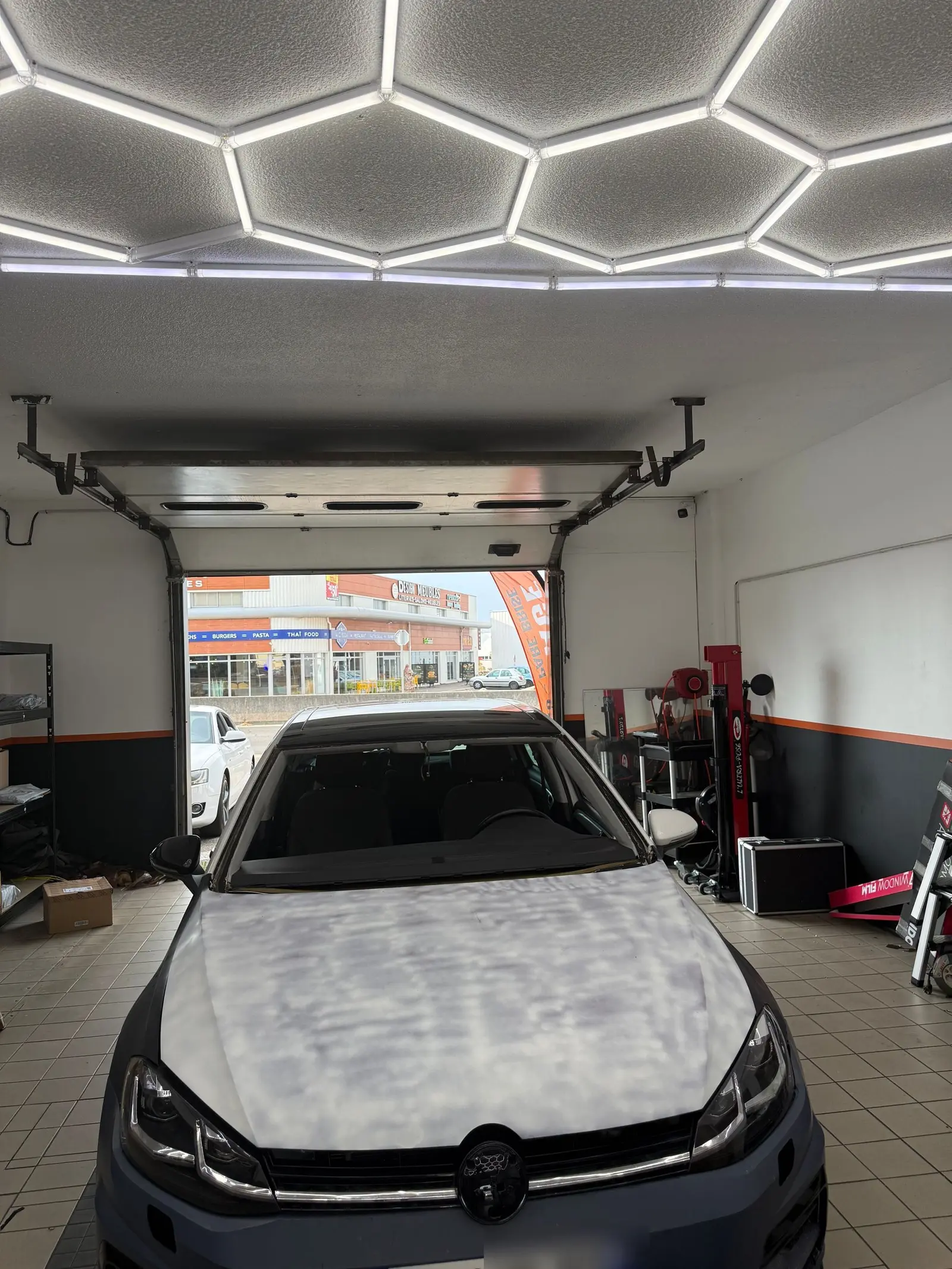 Intérieur de l'atelier Signature Glass à Cenon, plafond lumineux hexagonal et Volkswagen Golf grise