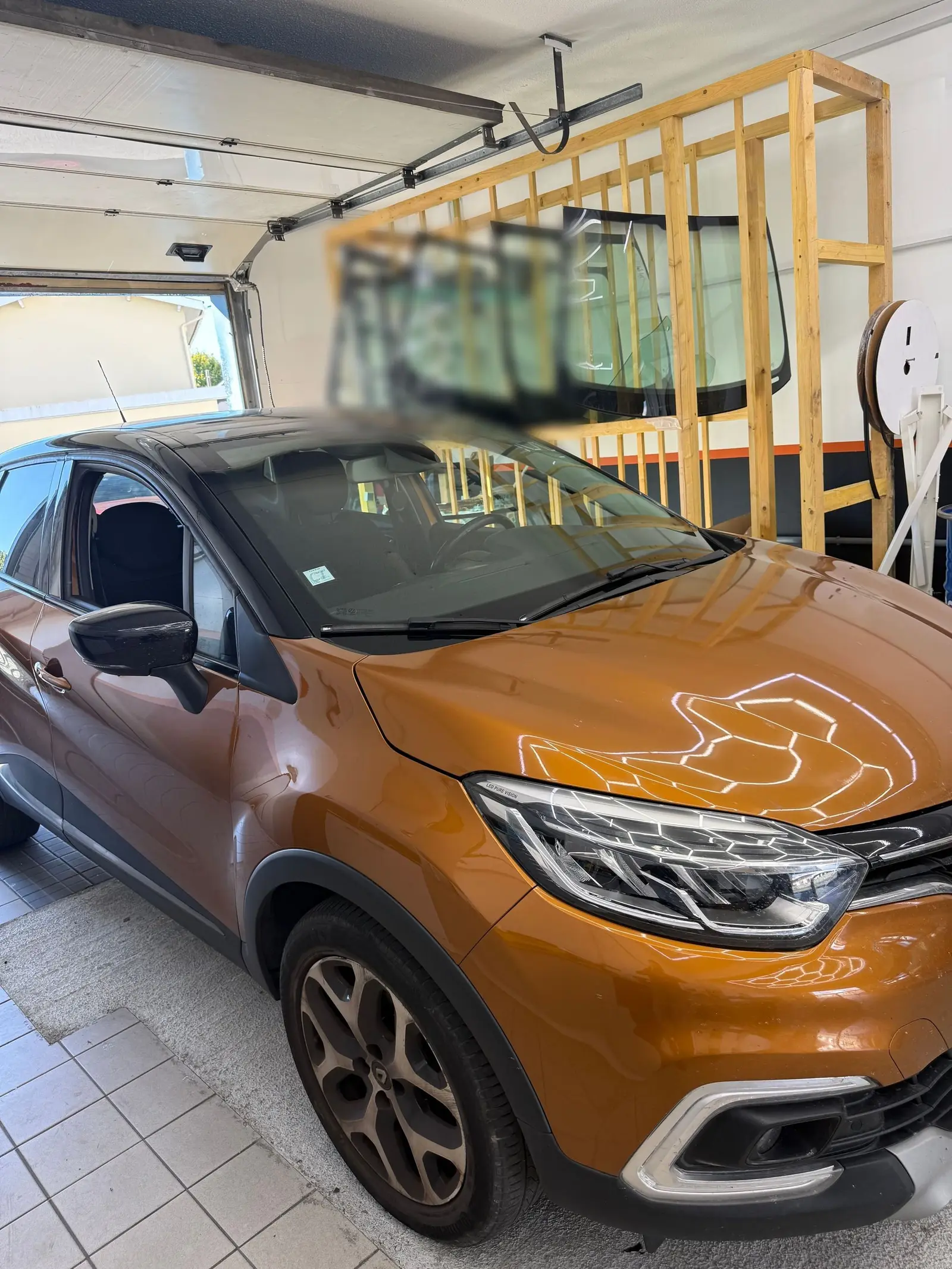 Renault Captur orange devant le rack de pare-brise neufs de l'atelier Signature Glass