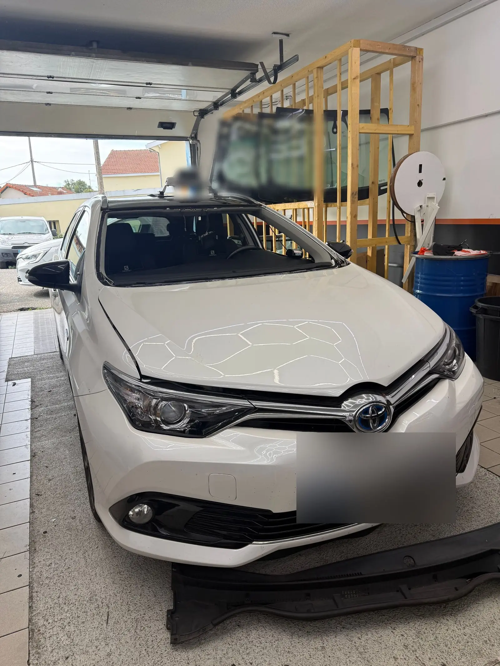 Toyota Auris blanche capot protégé, pare-brise en cours de remplacement dans notre atelier de Cenon